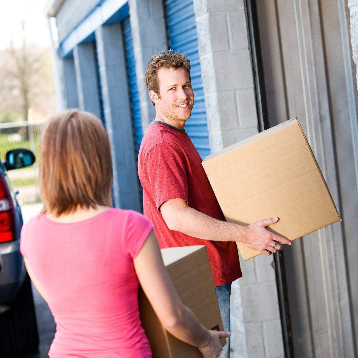 A man and a woman moving boxes into a storage unit